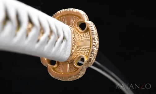 Tsuka mit weisser Seidenwicklung, schwarz-gold gemusterter Habutae-Unterlage und Messing-Tsuba