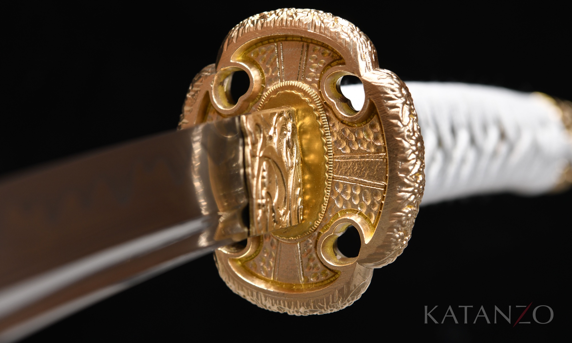 Tsuka mit weisser Seidenwicklung, schwarz-gold gemusterter Habutae-Unterlage und Messing-Tsuba